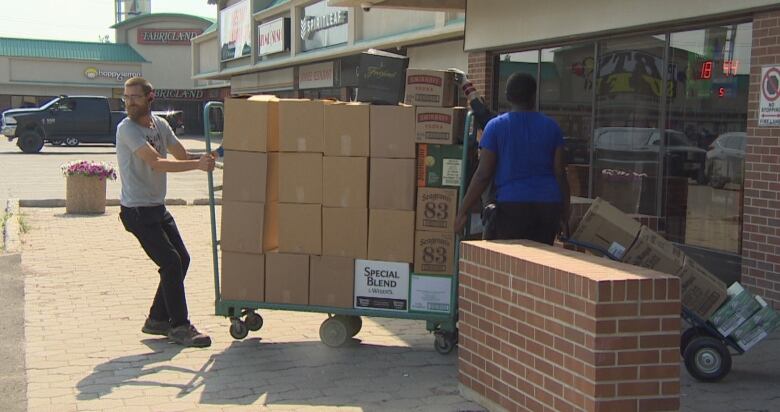 A man pulls a cart loaded with boxes