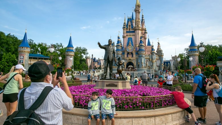 People take photos in a  crowd of  a castle in a theme park