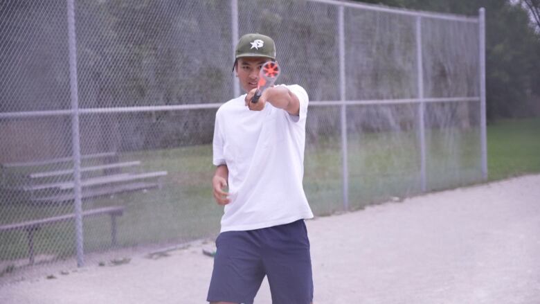 A man points a baseball bat at the camera. 