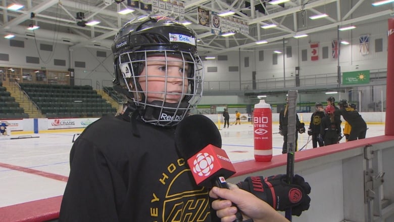 Girl in hockey jersey and helmet.