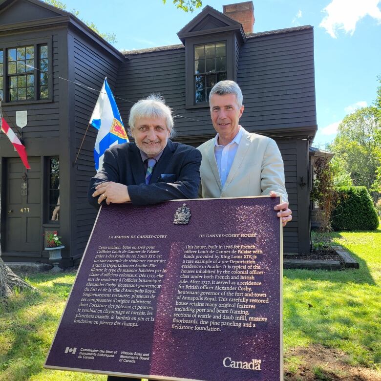 Historian Alan Melanson (left) and Alyn How, whose family owns the home, pose for a photo in front of the newly unveiled plaque at the Degannes-Cosby house.