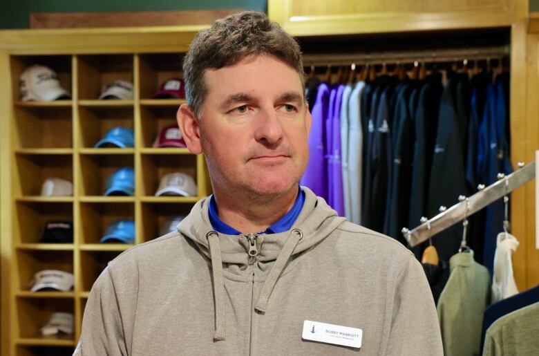 Bobby stands in front of clothing racks in the Granite Springs pro shop.