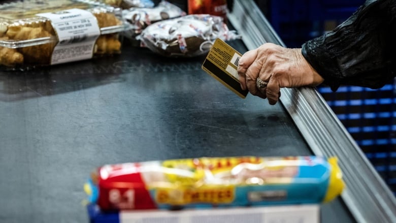 a person waits to pay with a credit card at a supermarket.