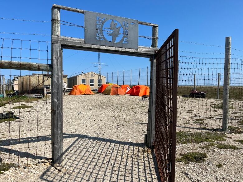 A fenced-in compound holds tents and buildings.