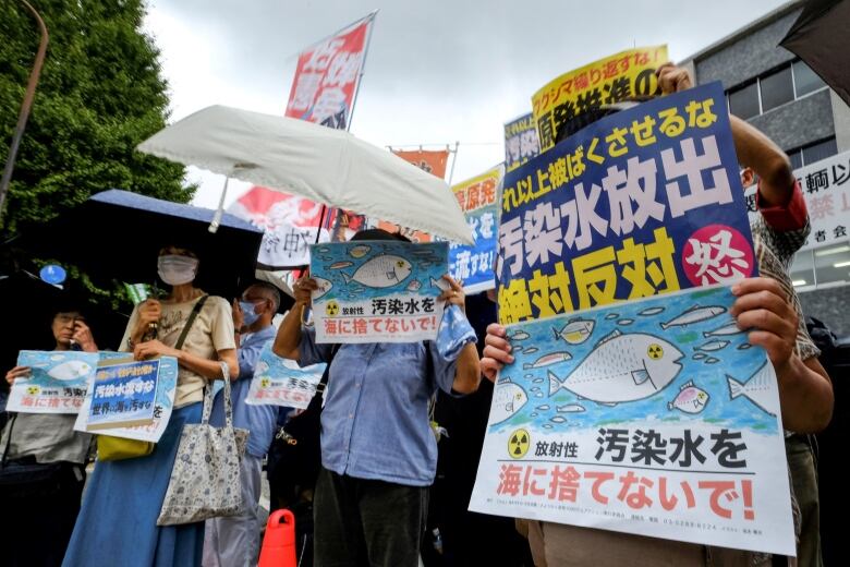 A line of people holding protest signs written in Japanese. 