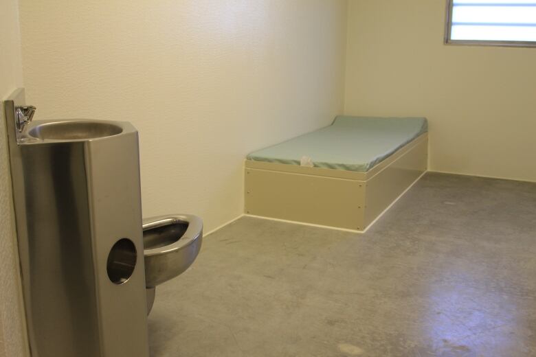 A single bed and toilet is pictured in a prison cell