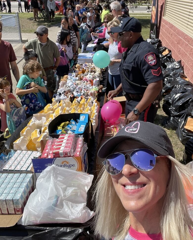 Martha Hart takes a selfie with the supplies table as children pick up their packages.