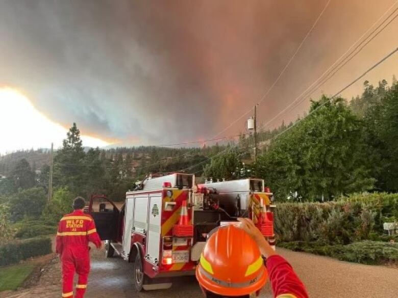 Firefighters are pictured with fire rescue vehicle under a black plume of smoke.