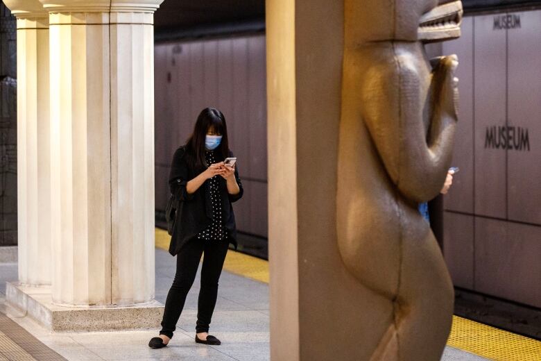 Commuters are photographed on their phones at Museum Station in Toronto, on Aug. 23, 2023.