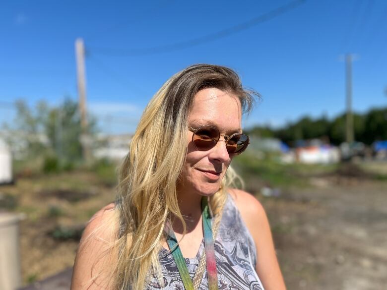 A woman stands in sunshine with sunglasses on