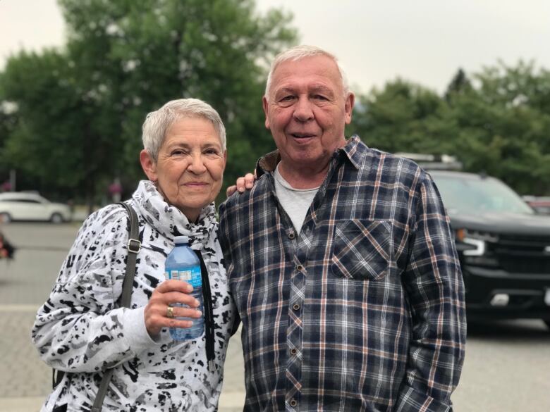 A retired couple poses for a photograph with their arms around each other.