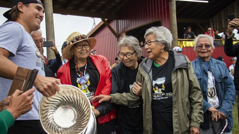 A young man carries the Stanley Cup for Indigenous elders to touch.