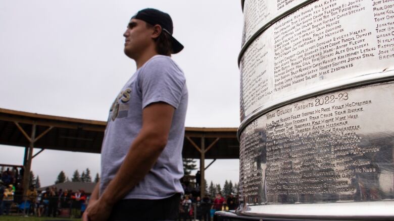 A young man stands by the Stanley Cup with the Las Vegas Golden Knights team members etched on it.