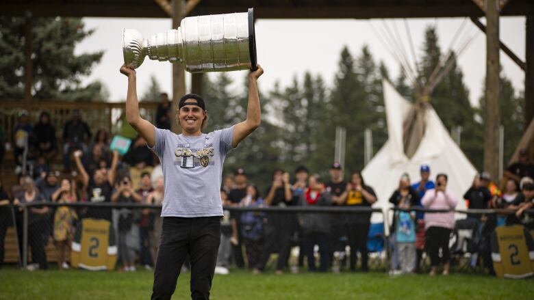 A young man carries the Stanley Cup.