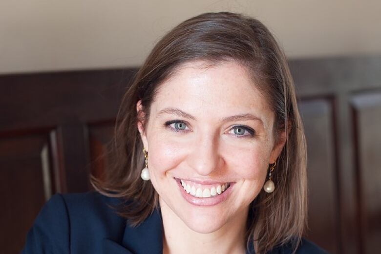 A woman with shoulder-length brown hair smiles at the camera. 