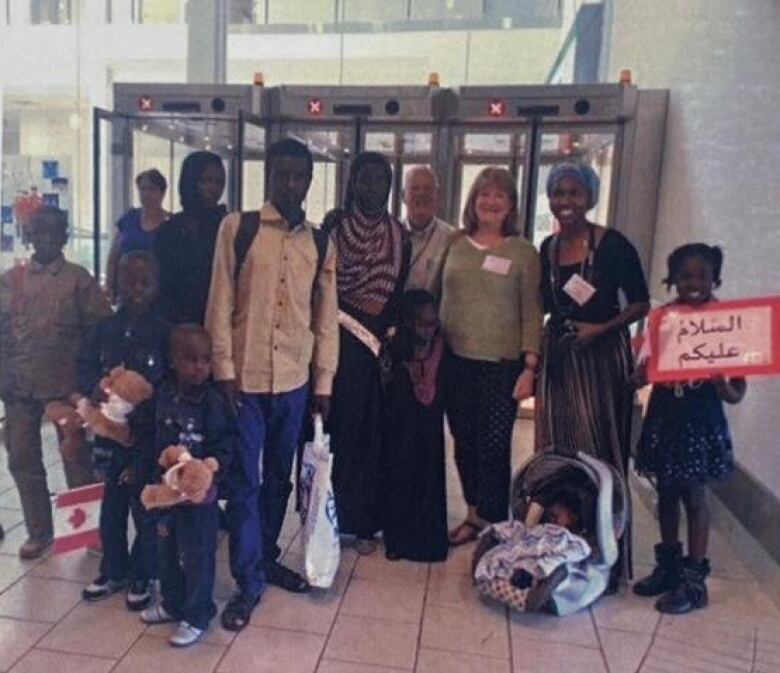 A group of eleven people pose at an airport terminal. 