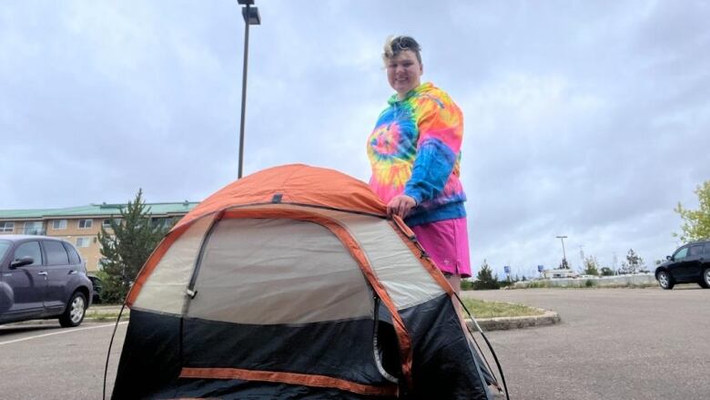 lady standing behind black and orange tent. 