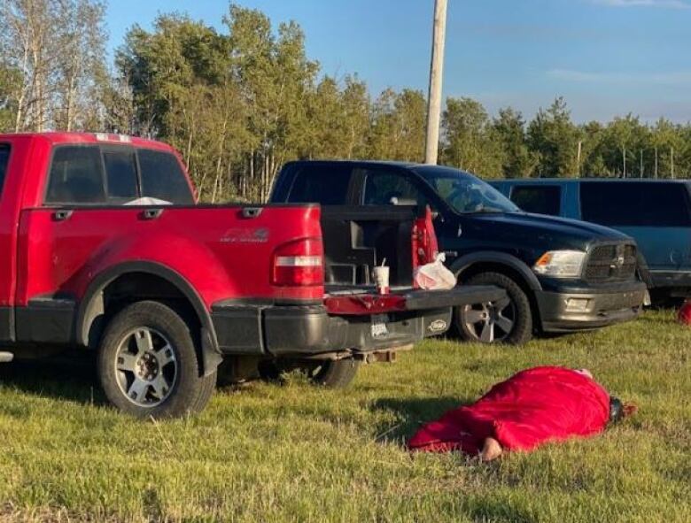 lady sleeping on grass in a red sleeping bag. 