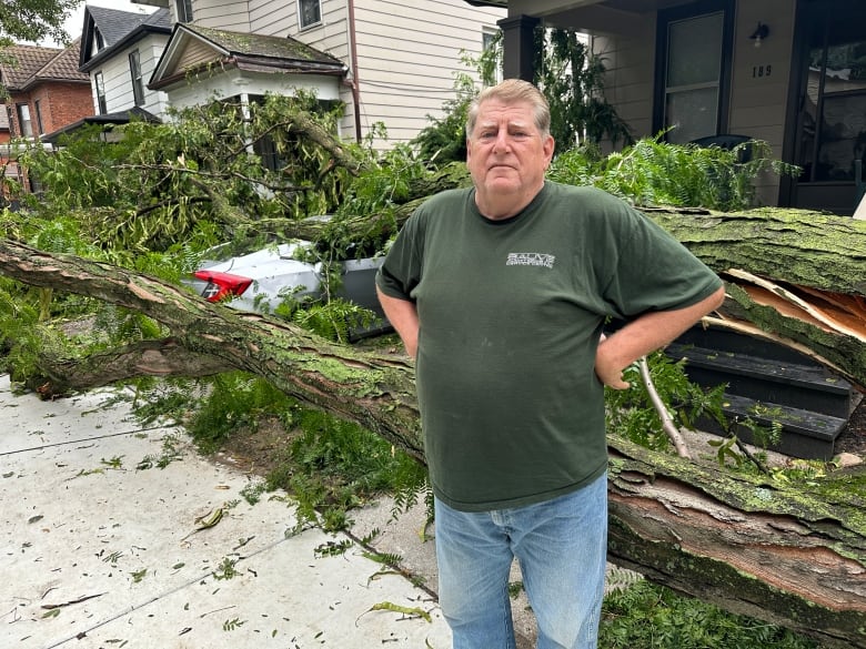 Gary Roberts, who lives on McKay Avenue in Windsor, Ont., stands in front of his property on Aug. 25, 2023. A neighbour's tree fell on top of his car parked in the driveway.