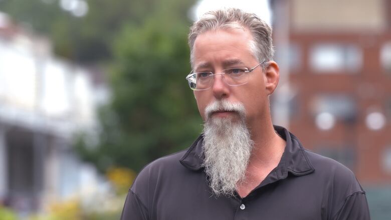 A man with a burly beard stares at the camera.