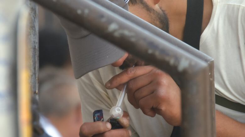 A man smokes from a crack pipe. 