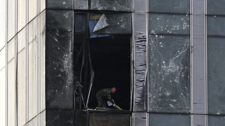 A man is seen cleaning up debris after a drone reportedly hit a Moscow office building.