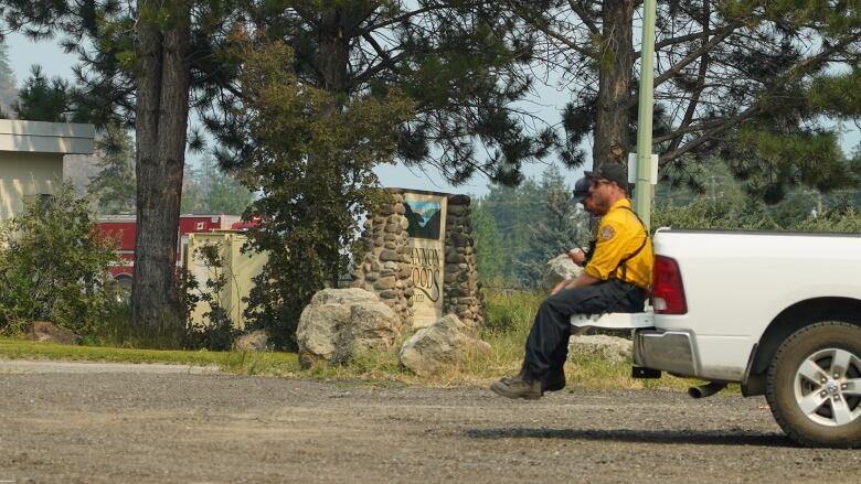 Two men wearing yellow perch on the back of a pickup truck.