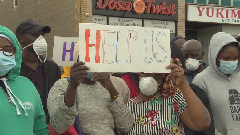 People in masks holding signs.