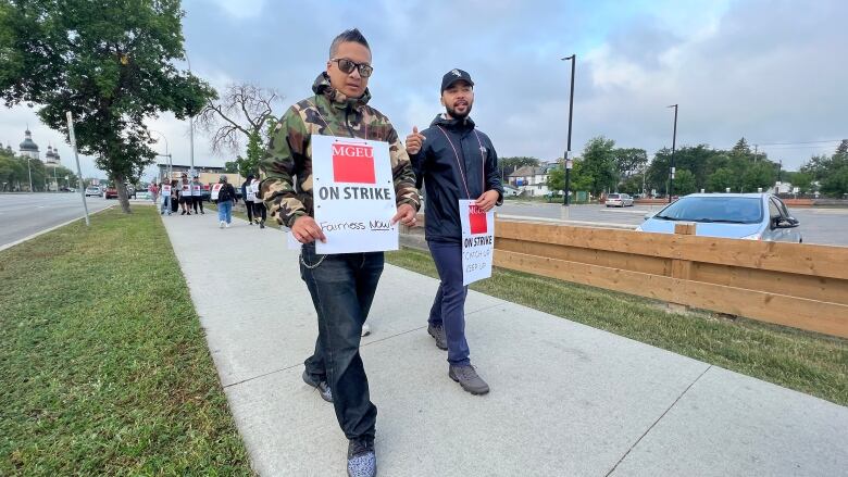 People walk a picket line on a sidewalk