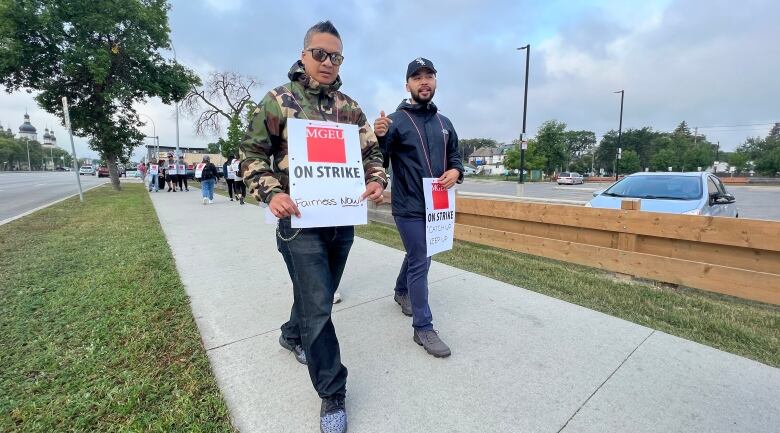 People walk a picket line on a sidewalk