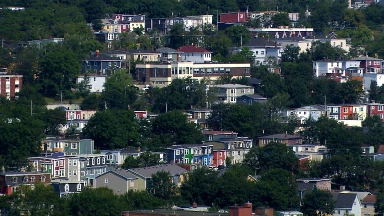 A view overlooking a city with houses accented by green trees. 