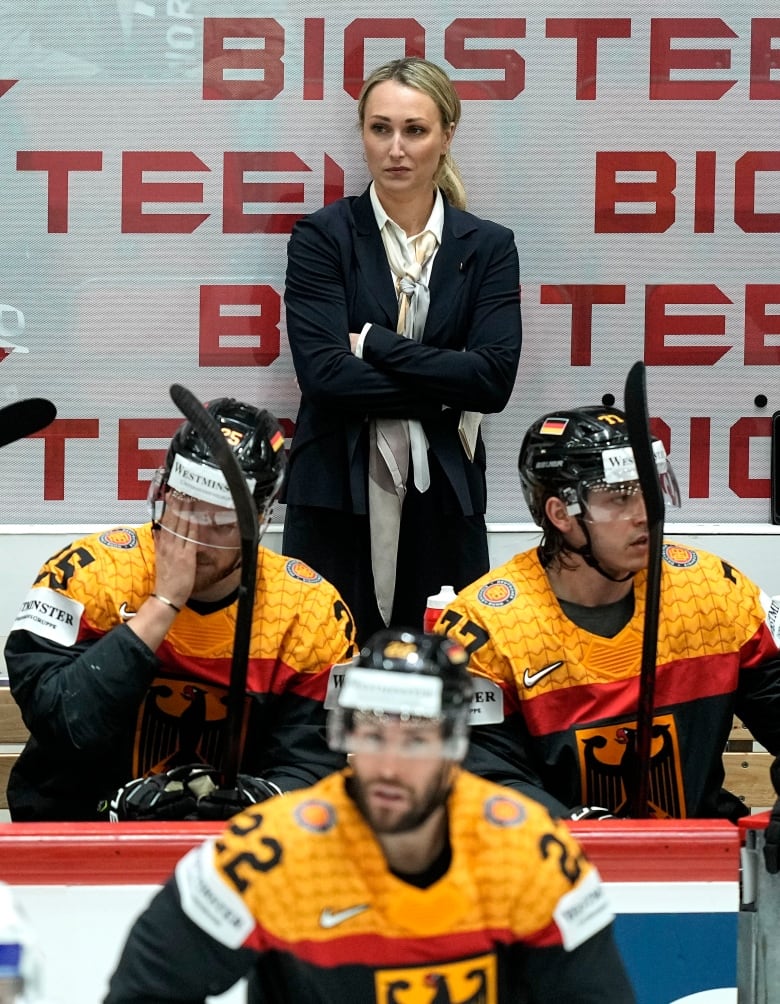 A woman stands behind a hockey bench.