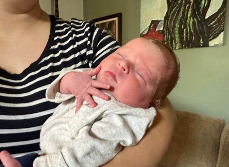 A close-up of a newborn baby girl being carried by her mother.