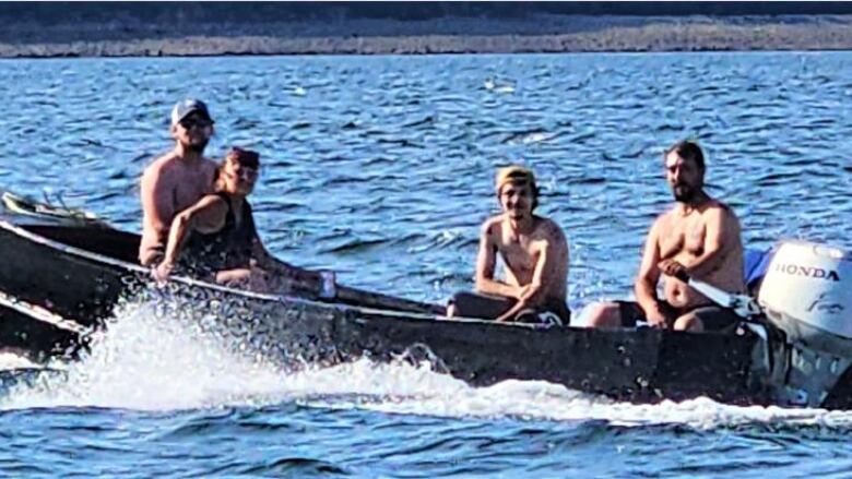 Three women and a man sit in a small motorboat as it moves through the water.