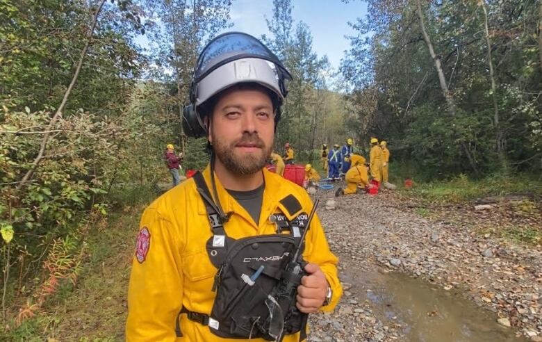 Man standing infront of a group of fire fighters in training.