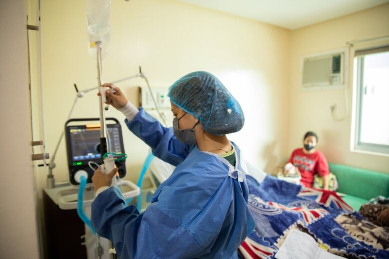 A nurse in blue scrubs in a patient room.