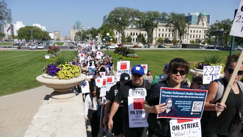 A long row of people arrive at a government building as part of a strike.