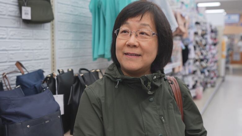 A woman looks at the camera and smiles in a store aisle.