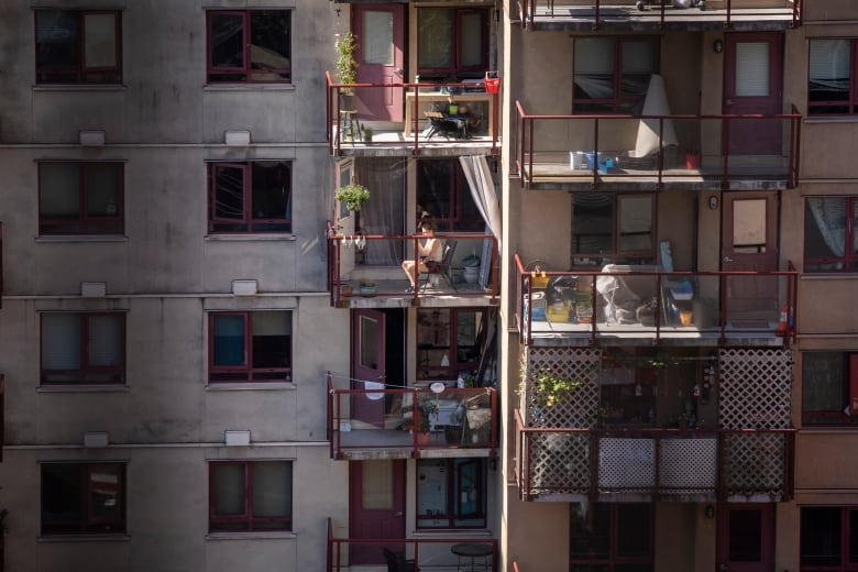 A woman sits on her balcony during a hot period of weather.