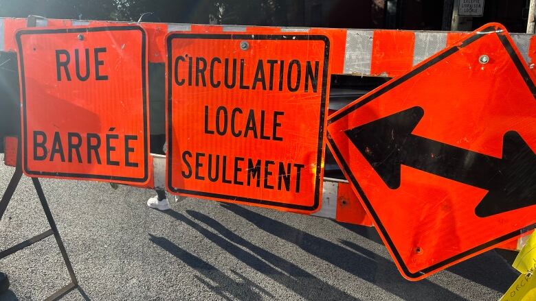 A roadblock with several signs attached to it saying 