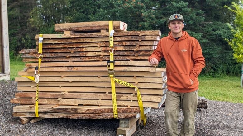 A man stands next to a section of tree cut into slabs 