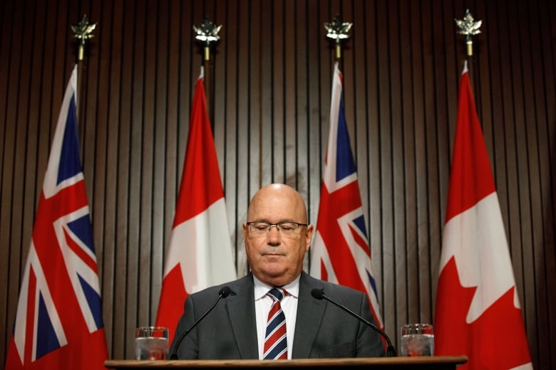 A man speaks behind a podium at a press conference.