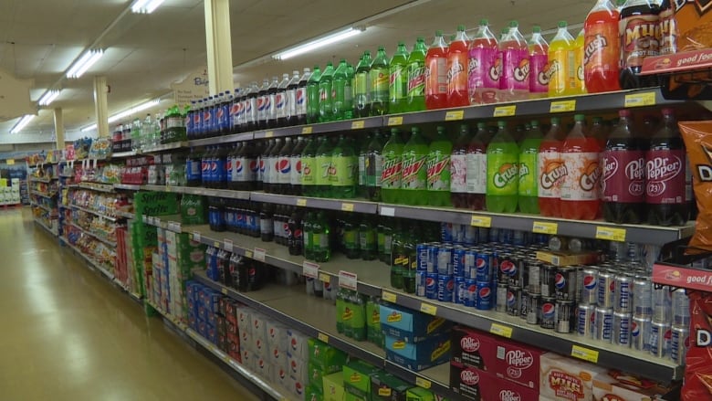 An aisle in a grocery store lined with soda bottles. 