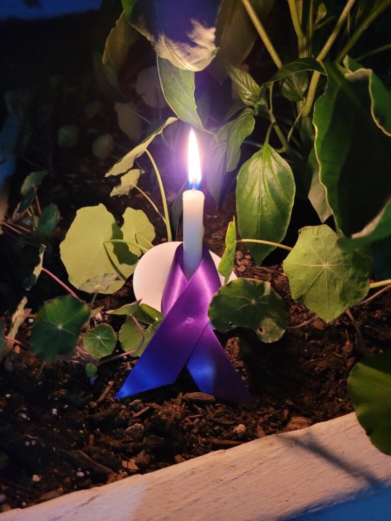 Candle lit and wrapped in a purple ribbon