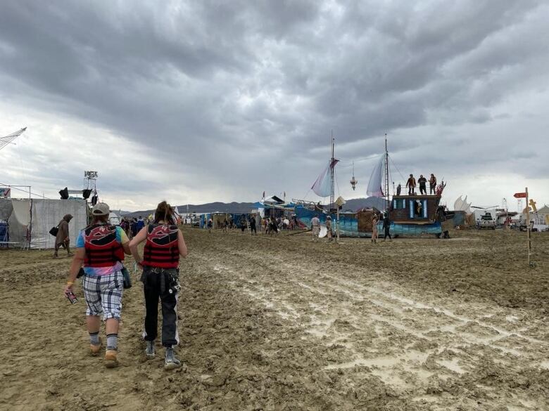 People walk through a muddy desert plain.