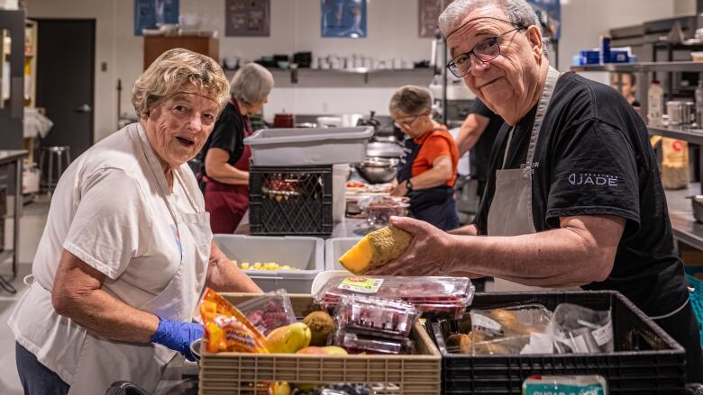 2 volunteers look towards the camera as they sort through food