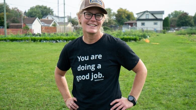 A smiling woman stands in a field.