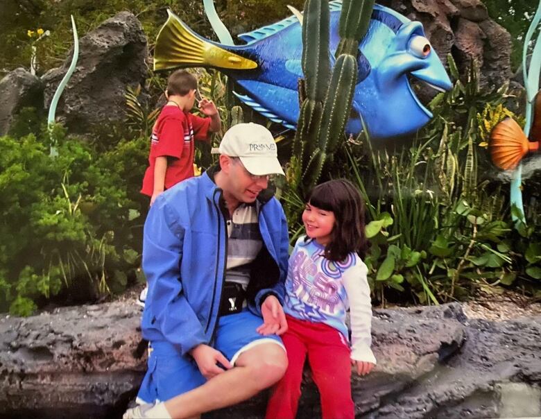 A man and a girl sit in an amusement park.