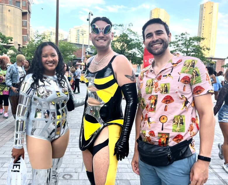 Three people stand outside a concert venue dressed up for a Beyonce concert.