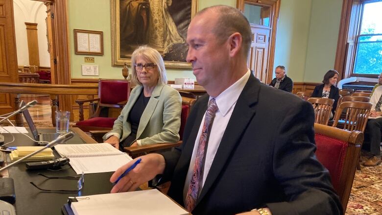 A man and a woman sit at a desk in the legislature.